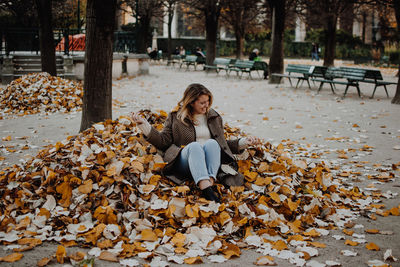 Portrait of young woman with autumn leaves in park