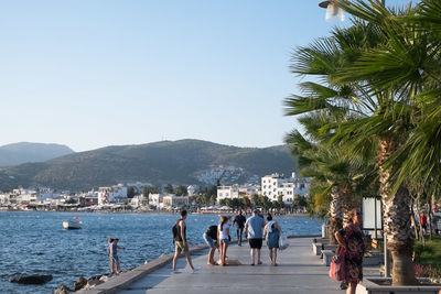 People by sea against clear sky