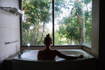 Rear view of mid adult woman sitting in bathtub