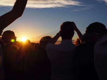 Rear view of people against sky during sunset