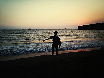 Silhouette of people standing on beach at sunset