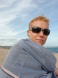 Portrait of man wearing sunglasses at beach against sky