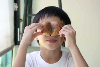 Close-up of playful boy holding food at home