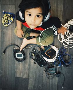 High angle portrait of cute boy listening music on headphones at home