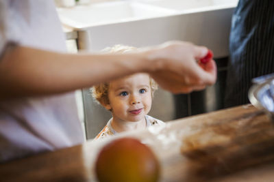 Boy looking at raspberry in kitchen