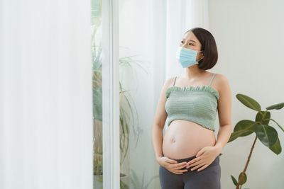 Pregnant woman standing by window at home