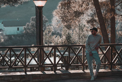 Man standing by railing against trees