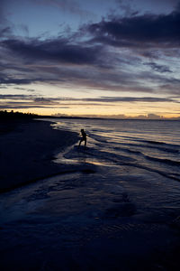 Silhouette man on beach against sky during sunset