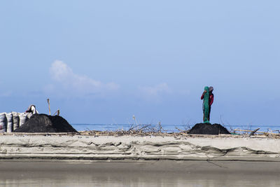 Statue by sea against blue sky