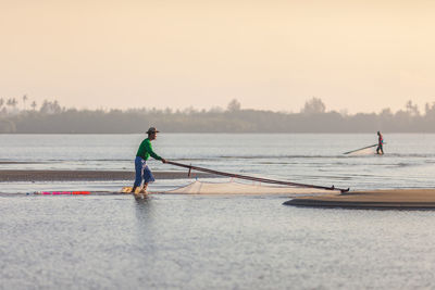 Men fishing on beach against sky