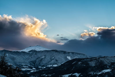 Scenic view of mountains against cloudy sky during winter