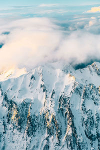 Aerial view of snowcapped mountains by sea against sky