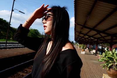 Beautiful woman shielding eyes while standing at railroad station platform