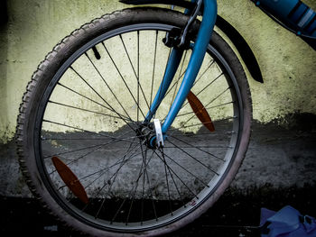 Close-up of bicycle wheel by wall