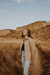 Young woman standing by plants against sky