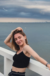 Portrait of young woman standing against sea