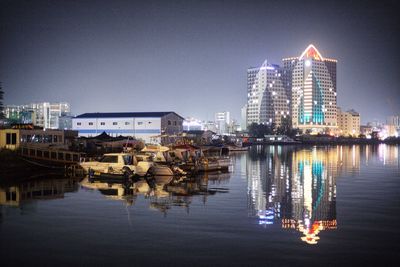 River by illuminated buildings against clear sky