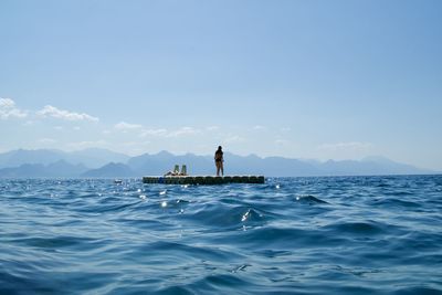 Man in sea against blue sky