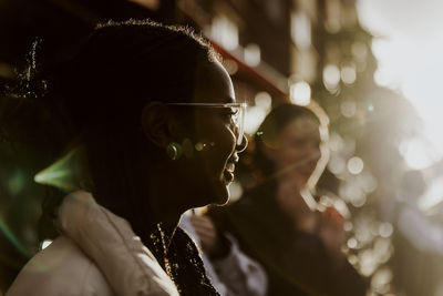 Smiling young woman wearing eyeglasses in city during sunset