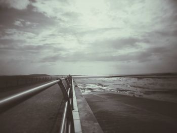 Pier on sea against cloudy sky