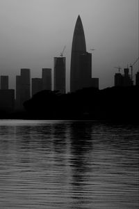 Modern buildings by river against sky in city