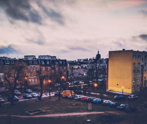 Illuminated buildings in city against sky at sunset