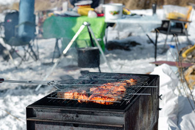 Winter barbecue outdoors, grill steak meat over hot coals in bbq at campsite cookout, camping mood