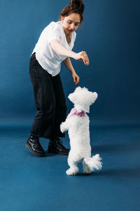 Side view of man with dog standing against blue background