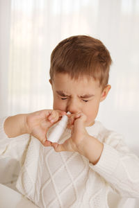 Little boy spraying medicine in nose, nose drops. toddler child using nasal spray. runny nose