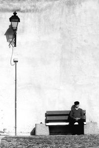 Rear view of man sitting on bench at street
