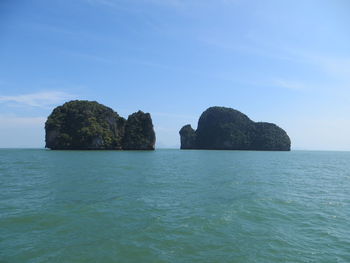 Rocks in sea against blue sky