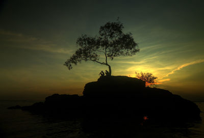 Silhouette people by trees against sky during sunset