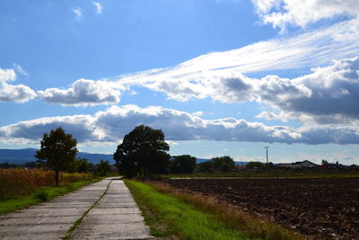 Road amidst field against sky