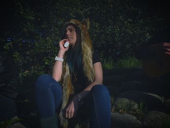 Woman wearing fake fur while sitting in forest