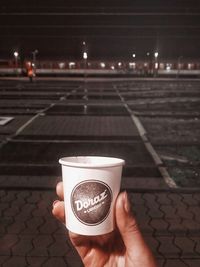 Person holding coffee cup at night