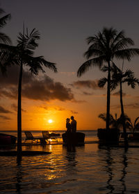 Silhouette people at beach against sky during sunset