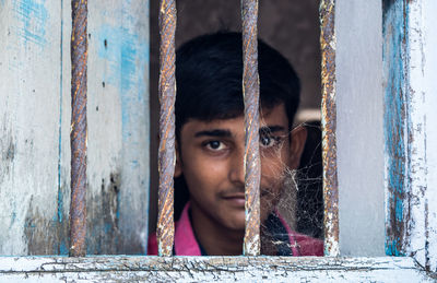 Close-up portrait of young woman against window