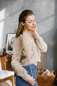 A beautiful young woman in jeans and a jumper gently holds a miscanthus herb in her hands person