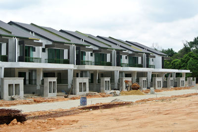 Buildings by construction site against sky in city