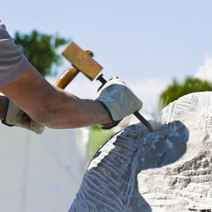 Close-up of man carving rock against clear sky