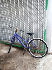 Bicycle parked by fence against wall