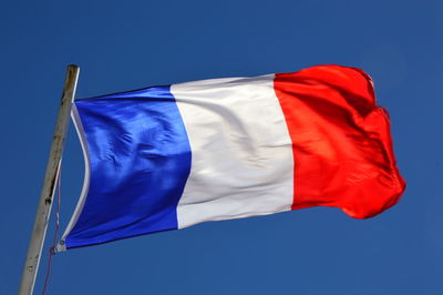 Low angle view of french flag against blue sky