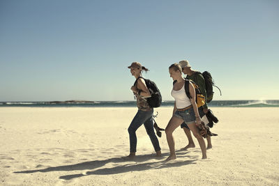 Male and female tourist walking on sand against sky during sunny day at weekend