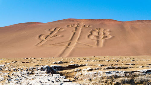 Sand dunes in desert against clear blue sky