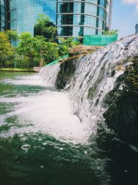 Scenic view of waterfall by buildings in city