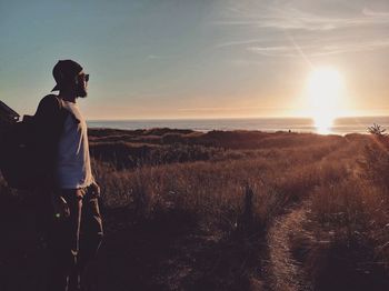 Man on field against sky during sunset