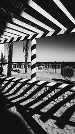 Shadow of railing on beach against sky