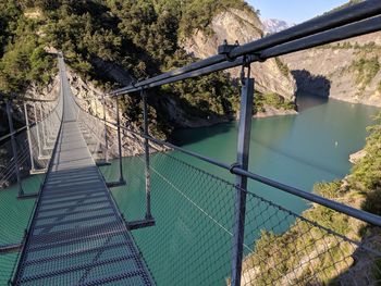 Footbridge over river against trees