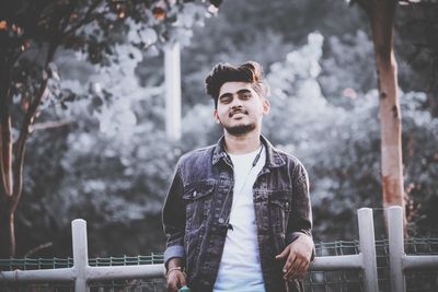 Young man looking away while standing against railing