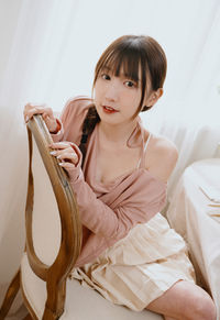 Portrait of young woman sitting on bed at home